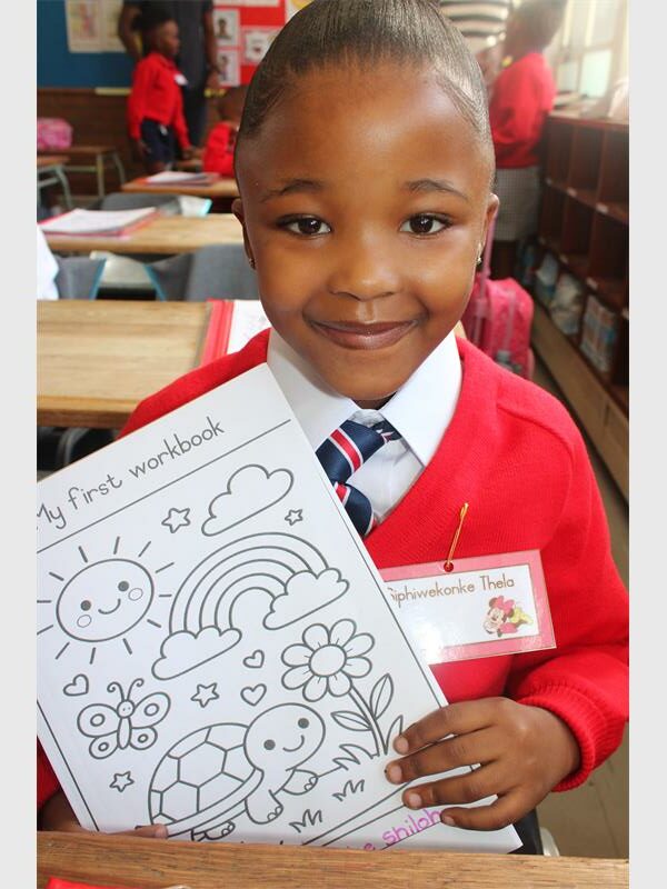girl in red school jersey holds up a colouring book