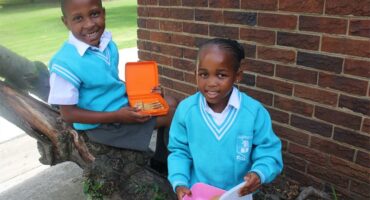 two kids in light blue school unforms eating lunch