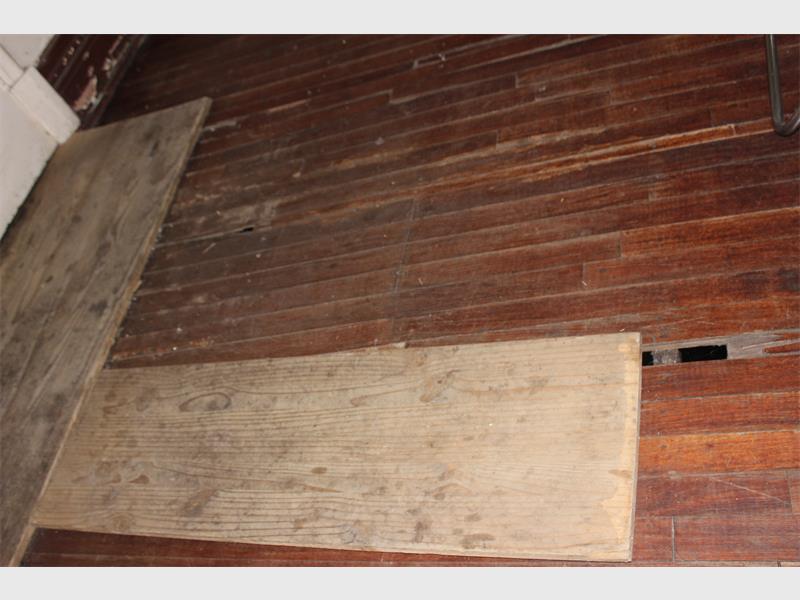 Floor renovation with new wooden planks on aged wooden flooring, fixing damage and improving space aesthetics.