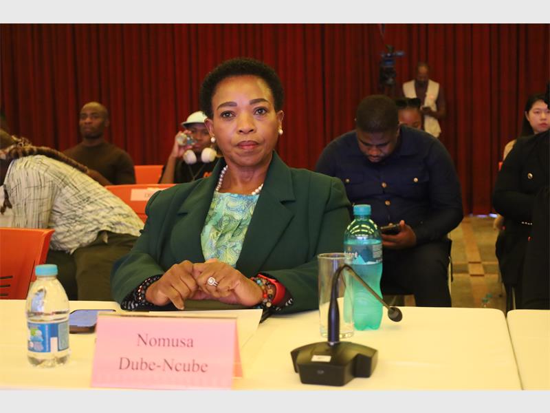 Woman sitting at a table with a microphone and a place card