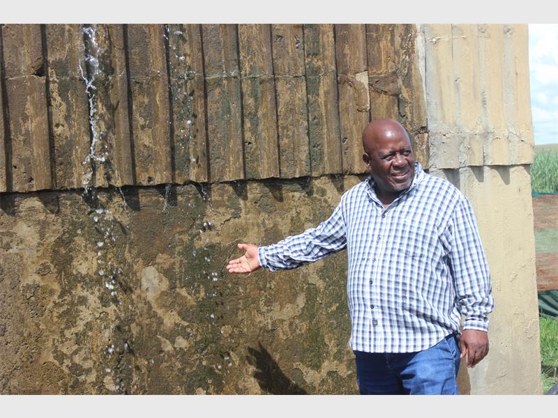 man points to water spilling from a reservoir