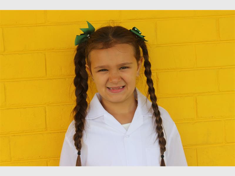 grade 1 girl in front of a yellow brick wall