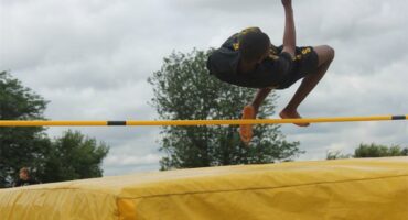 boy jumps over bar in high jump
