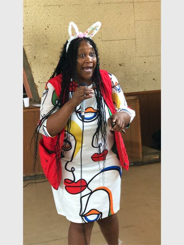 woman in a colourful dress in the front of a school hall