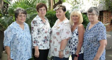 Five women pose in a line outside