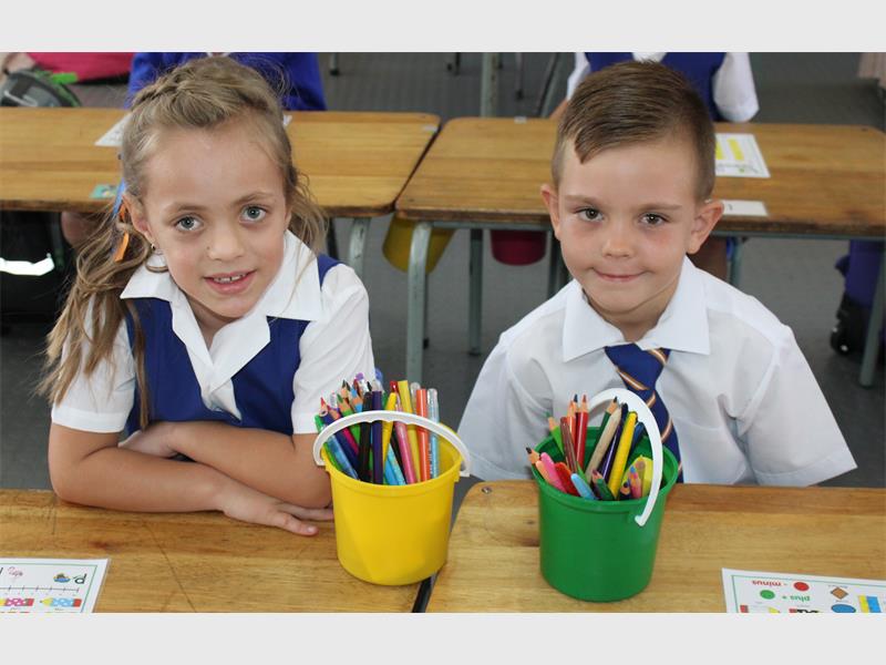 boy and girl sit at their school desks