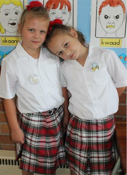 twin girls in school uniform with tartan skirts