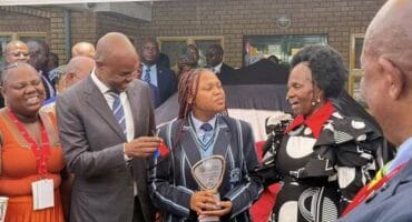 two adults flank girl with trophy