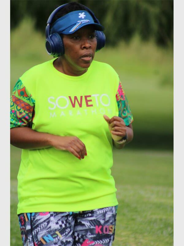woman in a neon yellow shirt and wearing earphones jogs