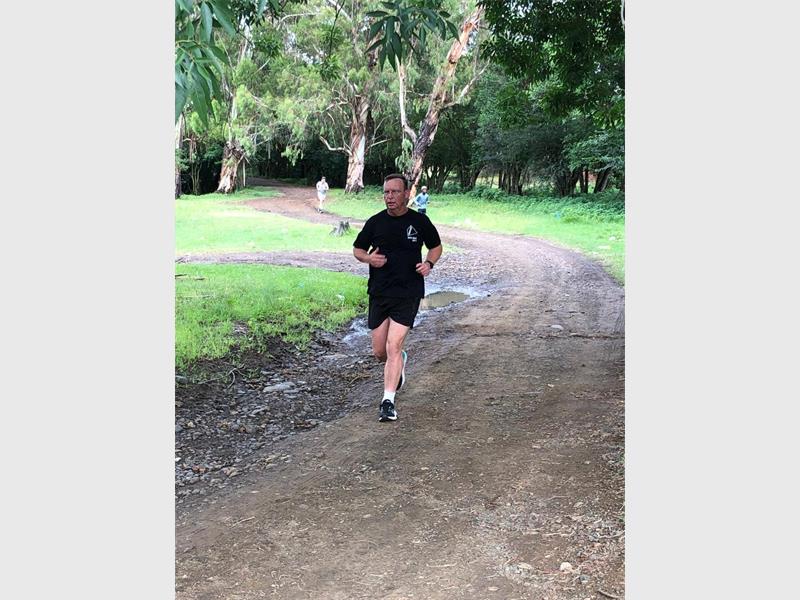 man in black pt clothes runs on a dirt road