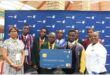 group of learners hold up a reward in front of a Sasol banner