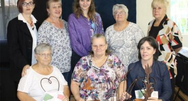 eight women at a table with trophies