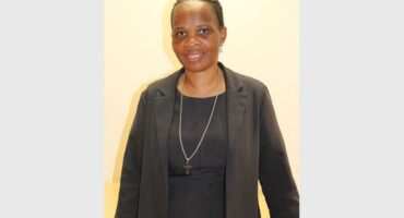 woman in a black dress in front of a pink wall