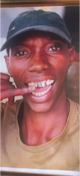 Young man with black cap and tan T-shirt smiles widely