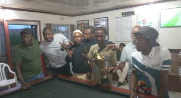 people flaunt a trophy around a pool table