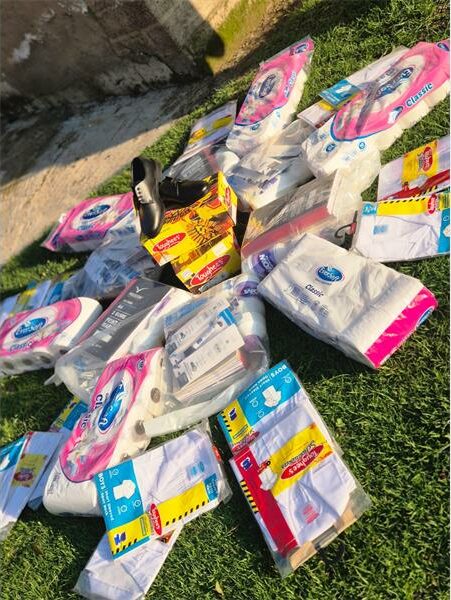 school items and sanitary pads displayed on a lawn
