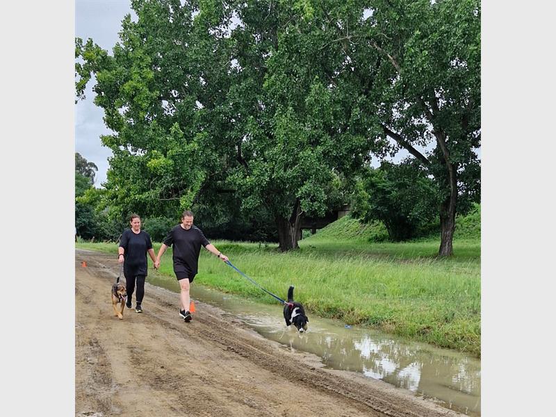 people walking their dogs on a muddy and wet road