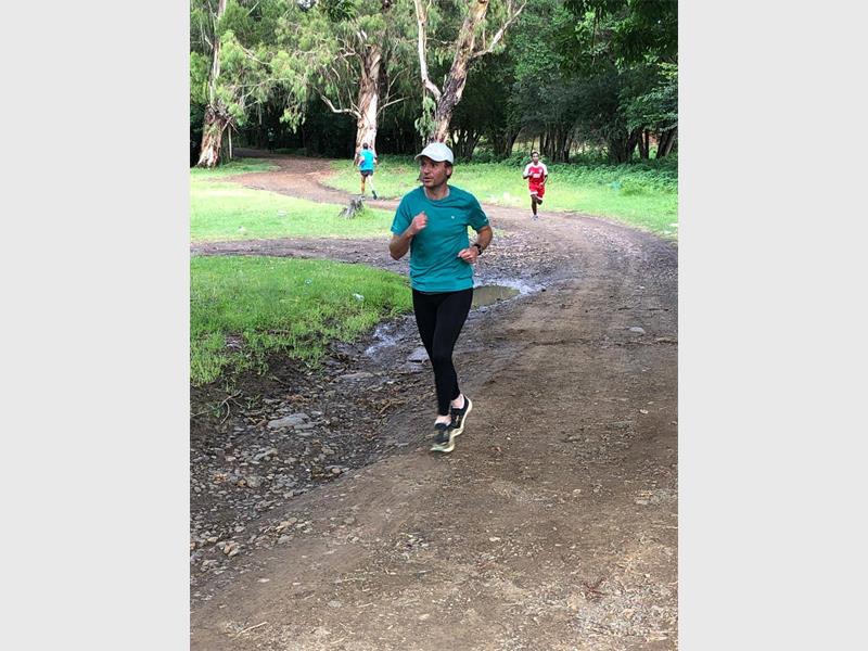 man with blue shirt runs in the park