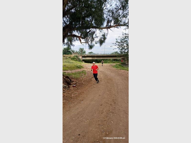 man with red t-shirt runs on a dirt road