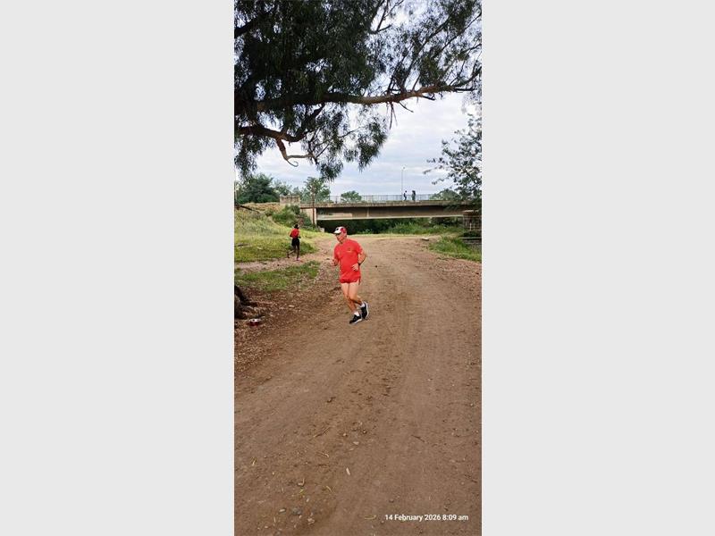 man with red t-shirt runs on a dirt road