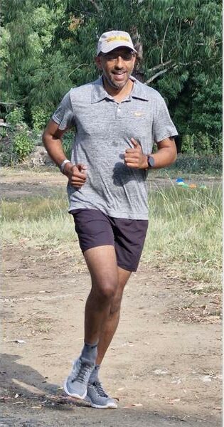 man in a grey shirt runs on a dirt road