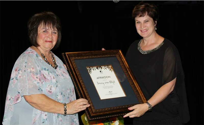 Two women wit ha framed certificate