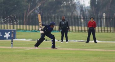 A batsman leans in to hit the ball