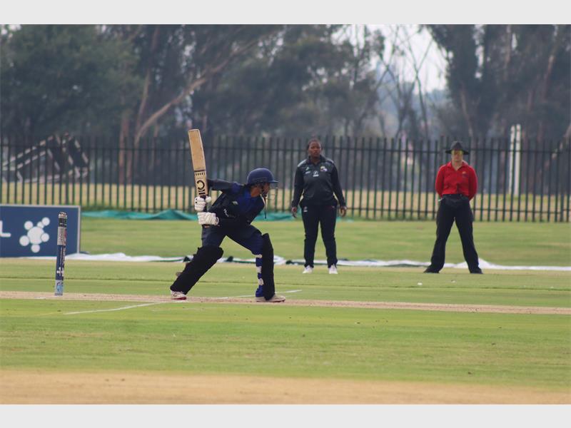 A batsman leans in to hit the ball