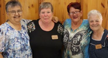 four women in front of a wooden wall