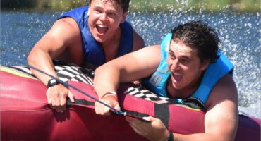 two boys hanging onto a tube being pulled on the water