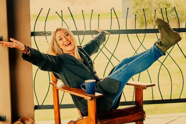 A woman in a chair with her legs and arms in the air.