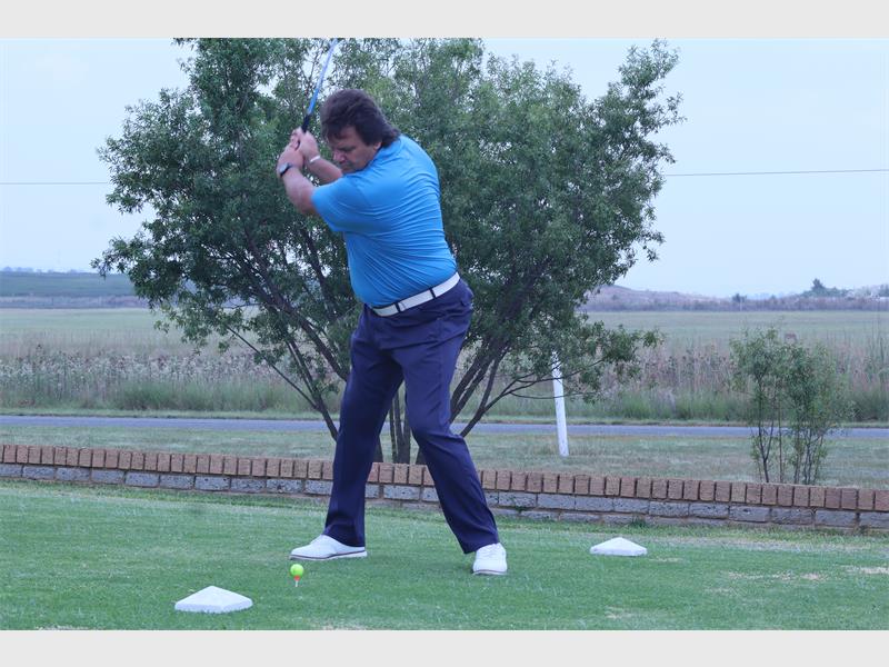 man with a blue shirt plays golf