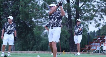 man in leopard print shirt and white shorts tee off