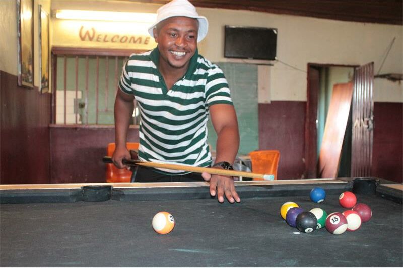 man with striped shirt plays pool