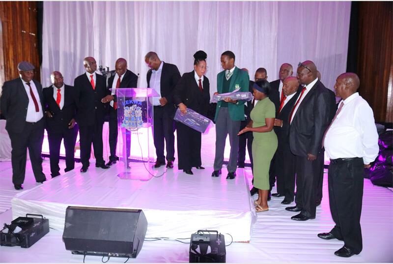 men in suits and red ties hand laptops to young people