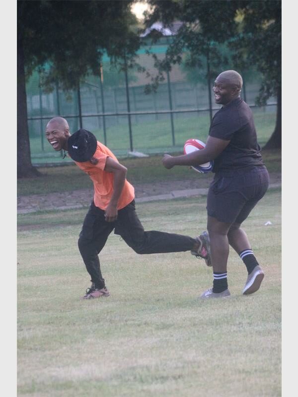 two men laughing while practicing rugby