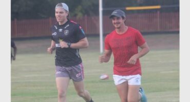 two young men jog on a rugby veld
