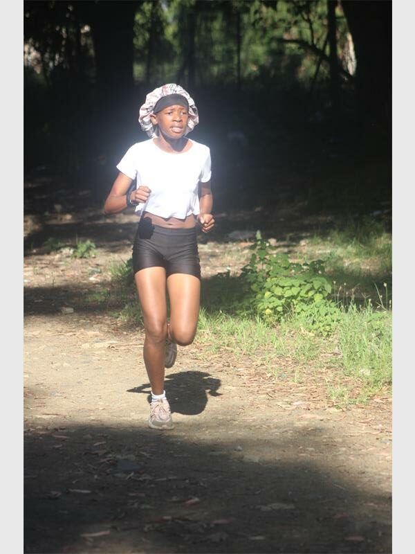 girl with sport clothes and a hair covering runs on a dirt road