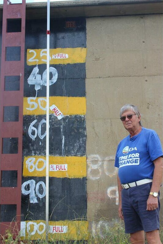 water reservoir with markings and a man next to it wears a DA T shirt