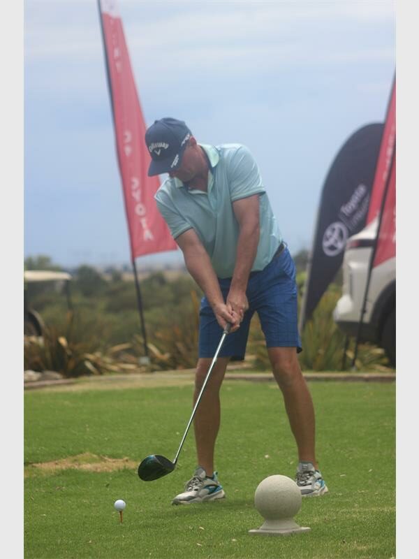 man with blue shirt and dark blue pants aims for the ball at the first tee