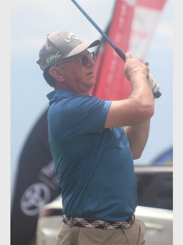 man with blue shirt an tan cap keeps an eye on the ball he just hit