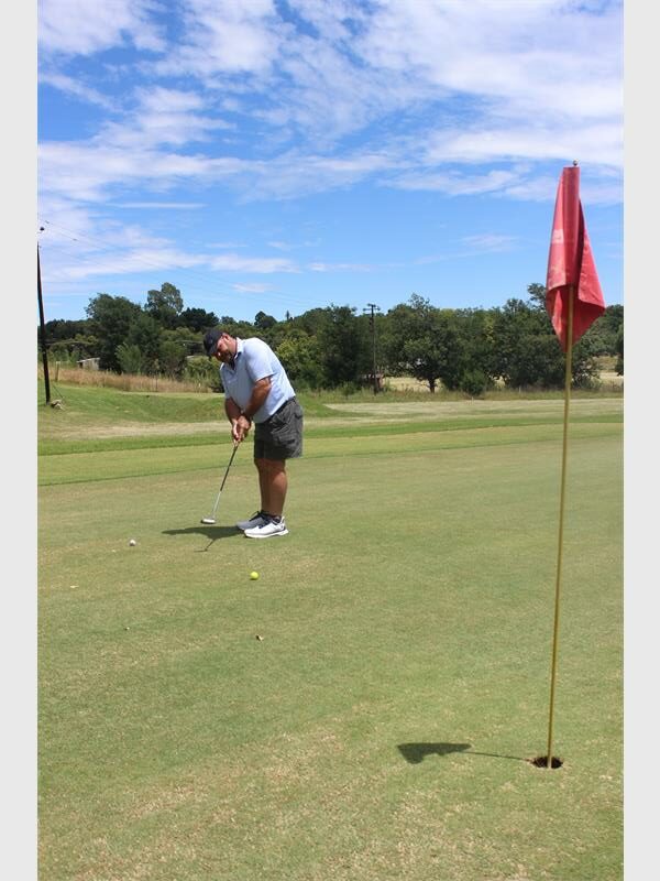 golfer in light blue shirt aims for the hole