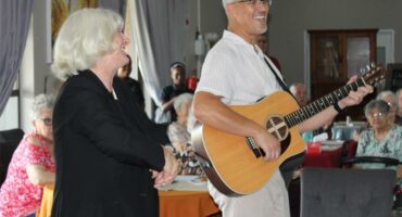woman signs and man plays guitar