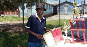 man shows off certificates and trophies