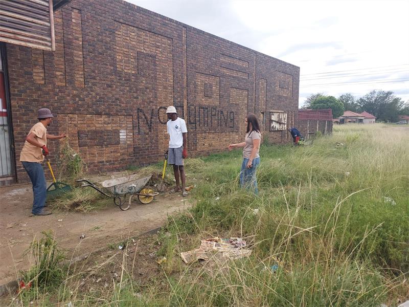 people clean up next to a building