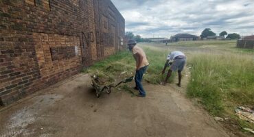 people clean up next to a building