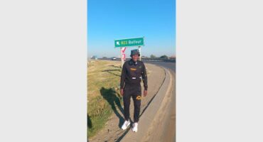 man stands in the road with a board marking of Balfour