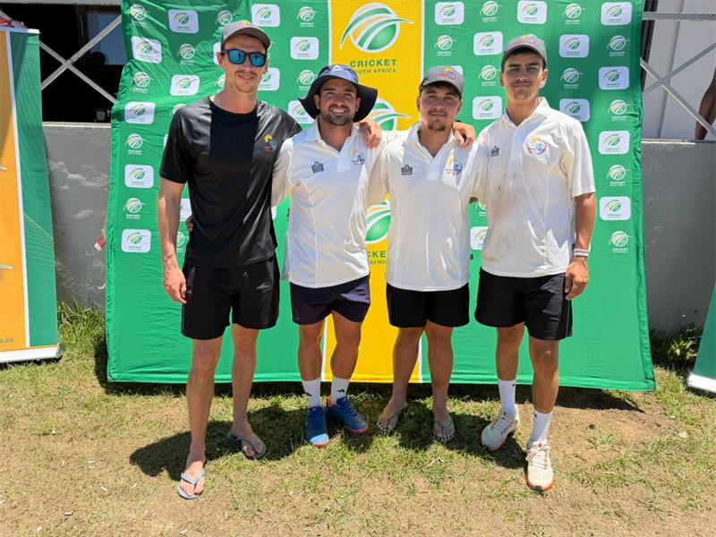 four men standing in front of a green and yellow cricket banner