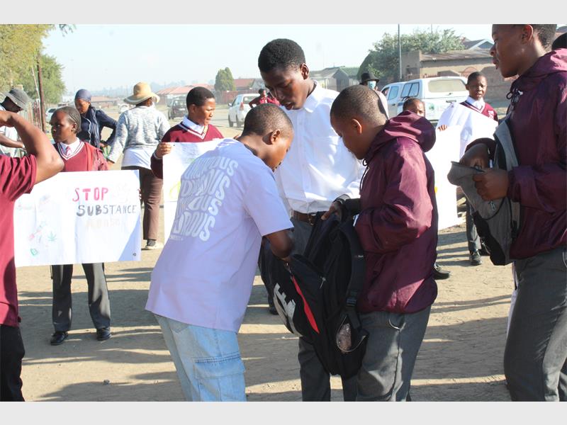 a man searches a learner's bag