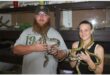 man and woman hold snakes around their necks